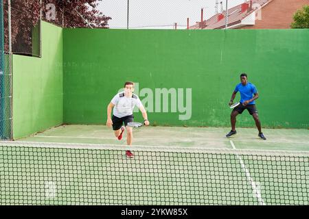 Two young friends playing paddle tennis on a court. Sports concept. Copy space Stock Photo