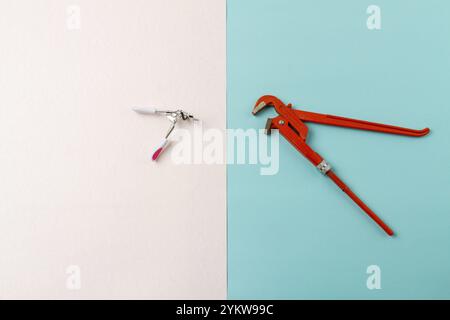 Top view contrast of mens and womens tools. Red adjustable wrench. White and turquoise surface Stock Photo