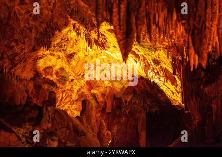 Stalactites and stalagmites in a cave illuminated by multi-colored light. A tourist attraction inside the mountain. Stock Photo