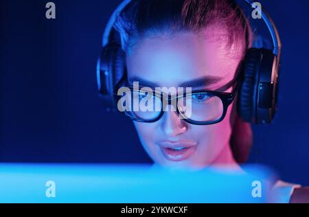 Female pro gamer playing video game, wearing headset Stock Photo