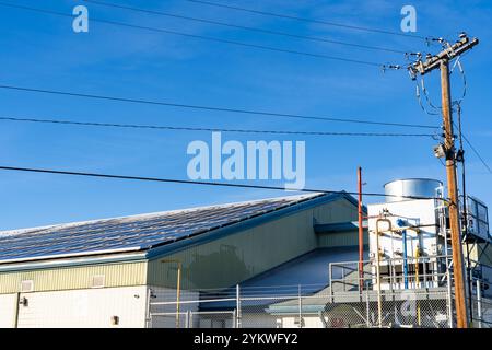 Solar panels with snow guards generating power with power lines and ice making equipment at a local community centre and hockey rink in Calgary Albert Stock Photo