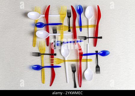 Top view colorful plastic utensils on white background. Forks with spoons and knives Stock Photo