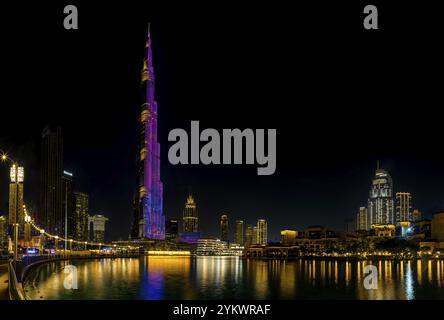 A picture of the iconic Burj Khalifa with its light show, and the surrounding Downtown Dubai buildings and Burj Khalifa Lake, at night Stock Photo