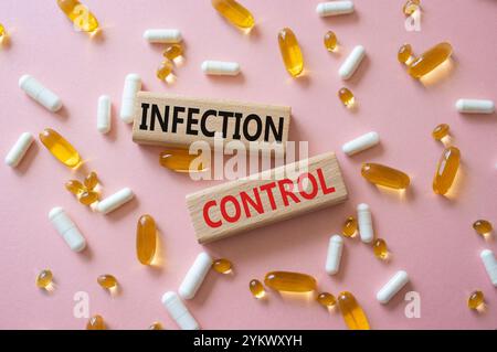 Infection Control symbol. Concept word. Infection Control on wooden blocks. Beautiful pink background with pills. Medicine and Infection Control conce Stock Photo