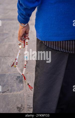 A woman pilgrim holding white mala beads in her hand while walking the kora around Boudhanath Stupa in Kathmandu, Nepal. Stock Photo