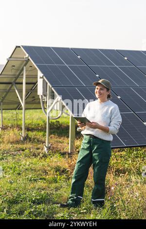 Female farmer with digital tablet on a modern farm using solar panels. Agricultural silos in the background.. Stock Photo