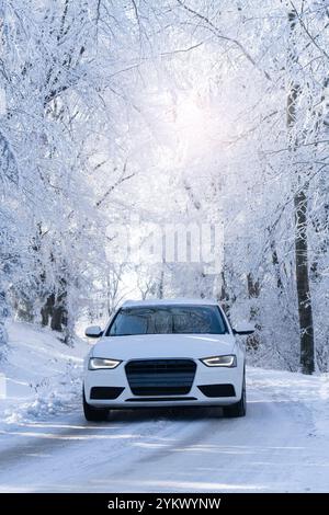Car on a winter road through a snow covered forest. Stock Photo