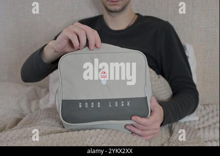 Man opening gray home first aid kit while sitting in bed Stock Photo