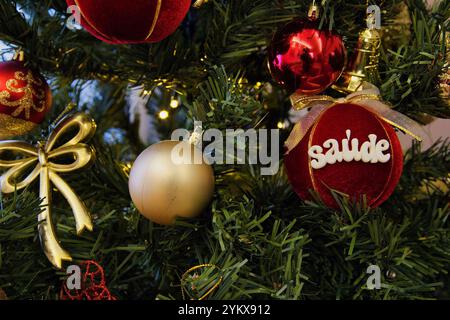 A Christmas tree with many ornaments and a red ball with the word saude written on it Stock Photo