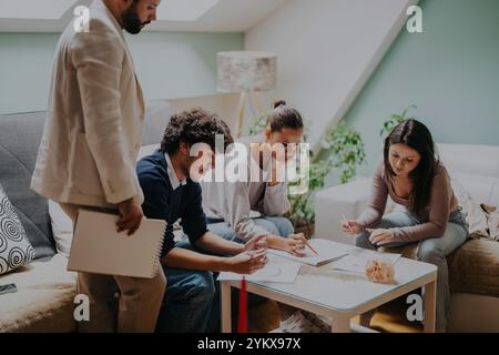 High school students work on a school project with their professor in a cozy home setting. Stock Photo