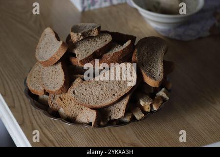 On the table is a plate with slices of black bread crackers. Stock Photo