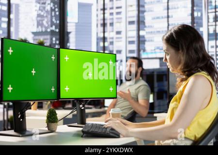 Developer using chroma key PC, fixing applications issues, dealing with databases and server configuration. IT expert using isolated screen multi monitor computer setup, optimizing company software Stock Photo