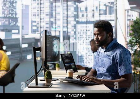 Computer scientist working with machine learning tech advancing AI critical to innovation of autonomous systems. African american IT expert in office transforming data into predictive models Stock Photo
