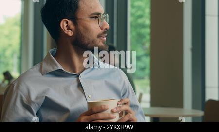 Indian ethnic man businessman drink coffee in cafe male guy visitor customer client freelancer tourist enjoy drinking tea beverage in restaurant order Stock Photo
