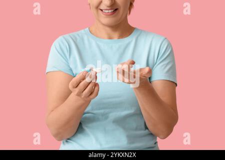 Mature woman with contact lens and case on pink background Stock Photo