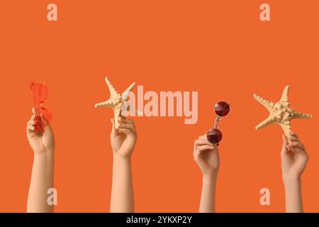 Female hands with stylish sunglasses and starfishes on orange background Stock Photo