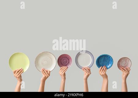 Hands holding empty plates on light background Stock Photo