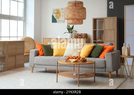 Comfortable sofa and tray with apricots on coffee table in interior of living room Stock Photo