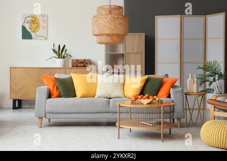 Comfortable sofa and tray with apricots on coffee table in interior of living room Stock Photo