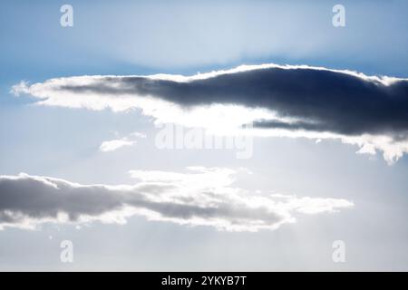 Bright blue sky filled with fluffy clouds and radiant sunbeams shining through. Clear blue sky adorned with soft clouds and golden sunbeams illuminati Stock Photo