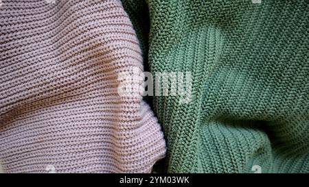 Background is filled with knitted fabric of different colors. Turquoise and purple. Clothing. Background is divided into two unequal parts by purple and turquoise knitted fabric. Hand made. Fashion. Stock Photo