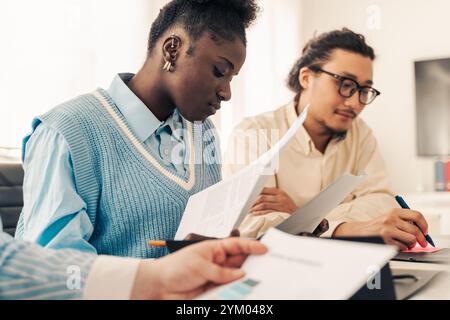 Diverse young business team reviewing documents during collaborative work session in modern office Stock Photo