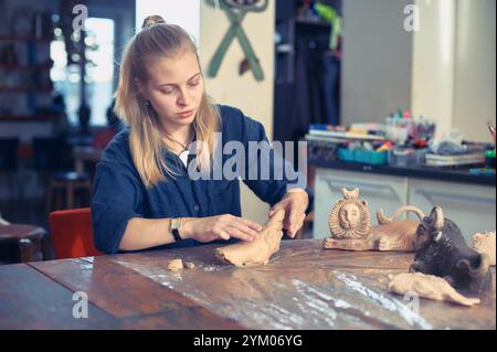 Young artist shapes clay into detailed sculptures in a bright studio atmosphere during an afternoon session Stock Photo