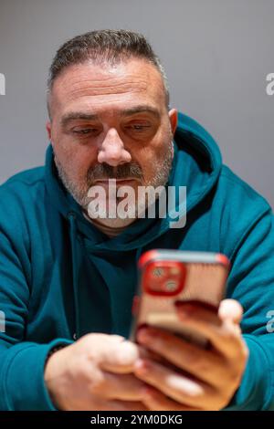Bearded man using smartphone, scrolling social media, reading latest news, checking email Stock Photo