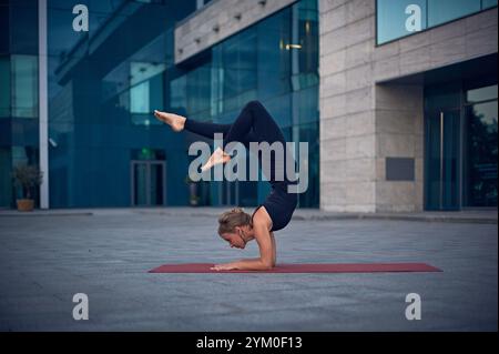 Practicing advanced yoga poses outdoors in an urban setting during the evening Stock Photo