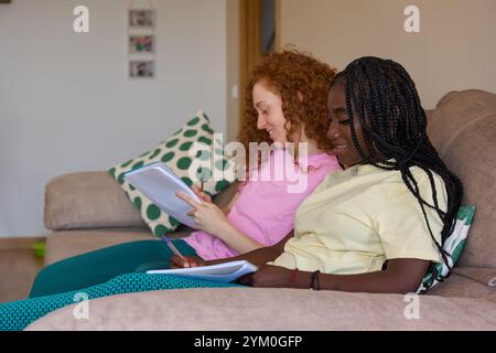 Students working on homework together on sofa at home Stock Photo