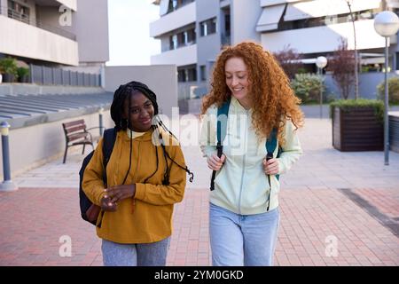 Two female students walking and talking on university campus Stock Photo