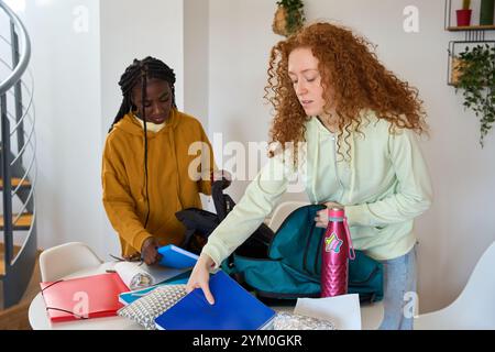 Students packing backpacks after studying together at home Stock Photo