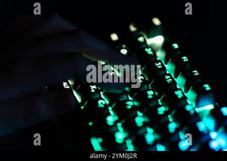 hand on the keyboard, typing on the keyboard, working at the computer. A teenager plays a video game on the computer at night. Stock Photo