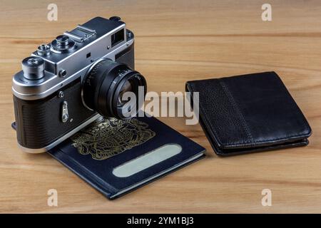 Old film camera and passport with leather wallet on a wooden table top travel concept Stock Photo