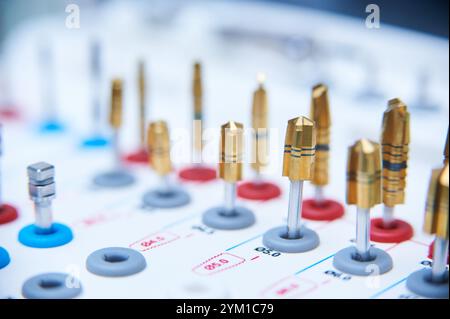 Dental implant surgery tools on a white surface. Close-up of golden drill bits and precision instruments in a medical or dental clinic setting. Stock Photo