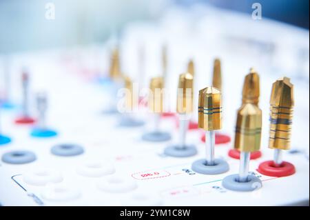 Dental implant surgery tools on a white surface. Close-up of golden drill bits and precision instruments in a medical or dental clinic setting. Stock Photo