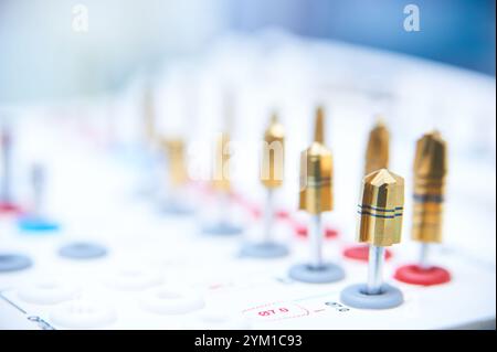 Dental implant surgery tools on a white surface. Close-up of golden drill bits and precision instruments in a medical or dental clinic setting. Stock Photo