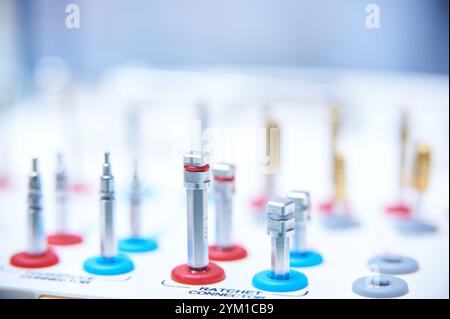 Dental implant surgery tools on a white surface. Close-up of golden drill bits and precision instruments in a medical or dental clinic setting. Stock Photo