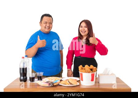 A Happy Couple Enthusiastically Enjoying Fast Food with Bottled Drinks on their Table Stock Photo