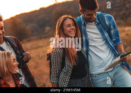 Group of four friends hiking through countryside together at sunset. Stock Photo