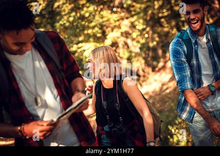 Group of four friends having fun hiking through forest together. Stock Photo