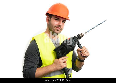 Adult male builder in work attire fluorescent vest and orange safety hardhat smiling as holding power tool for drilling trades industry job concept is Stock Photo