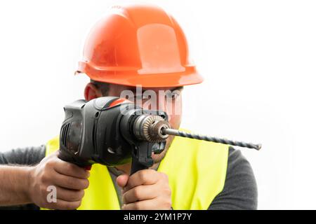 Close-up of adult male constructor wearing helmet and fluorescent vest using cordless power drill tool isolated on white background Stock Photo
