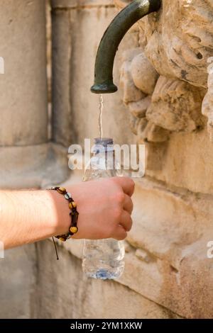 Young girl fills water bottle from monkey sculpture facemask outlet on Large Onofrio Fountain / Big Onofrios Fountains. Poljana Paska Miličevića sqare. Dubrovnik old town. Croatia. (138) Stock Photo