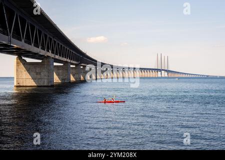 Kayakers in a tandem sea kayak pass under the Oresund bridge, a railway and motorway cable-stayed bridge between Denmark and Sweden. Stock Photo