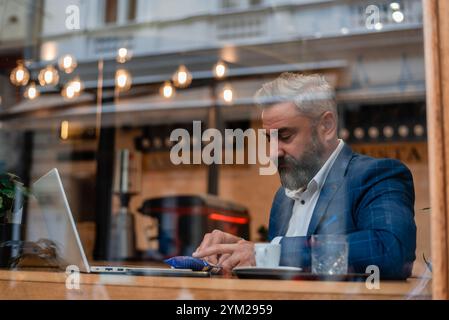 A happy mature business man using his laptop at a restaurant cafe. Stock Photo