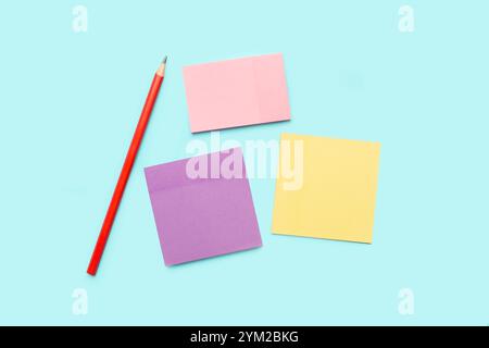 A pencil and colored paper notes on a light blue background Stock Photo