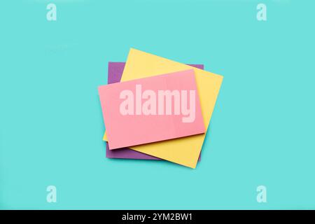 A pile of colored paper notes on a light blue background Stock Photo