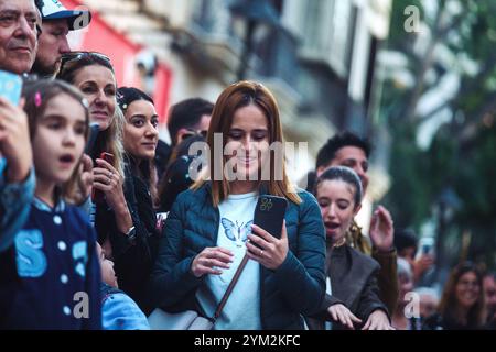 crowd of people, and they appear to be focused on an event or something of interest not shown in the photo. woman with reddish-brown hair who is Stock Photo