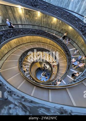 Aerial view of a busy spiral staircase with people ascending and descending, highlighting the ornate railings. The Vatican Stock Photo